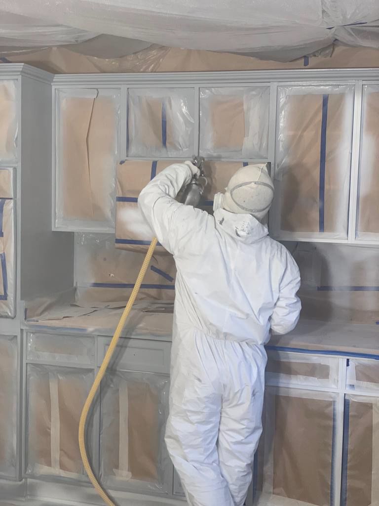 Spraying cabinet frames inside a fully covered kitchen