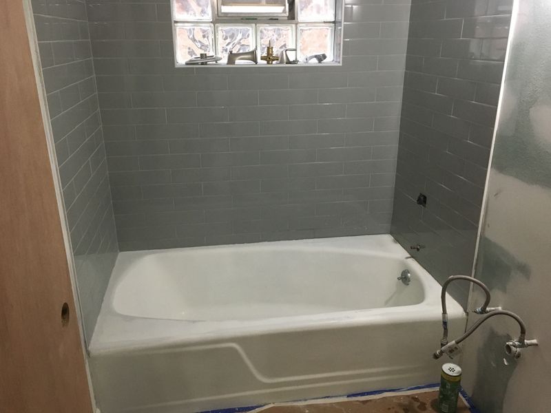 Refinished bathtub in a gray tiled bathroom